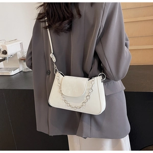 Detailed side view of a white leather crossbody bag with flower metal chain on a model