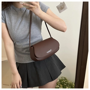 Detail of dark brown leather oval shoulder bag with white Fashion print and slim strap