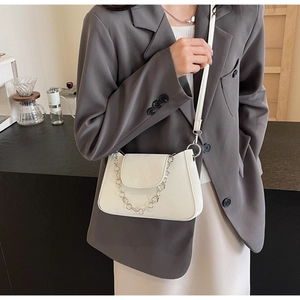Détail du sac à épaule en cuir blanc avec chaîne décorative en métal à fleurs argentées