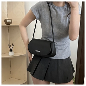 Detail view of a black PU leather shoulder bag with Fashion lettering shown on a model