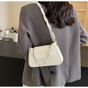 Détail d'un sac blanc avec chaîne florale et bandoulière tressée élégante