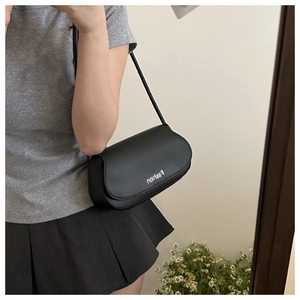 Mirror selfie showing a black leather shoulder bag with white fashion text print