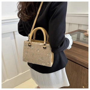 Detailed close-up of straw woven handbag with floral embroidery and brown leather trim
