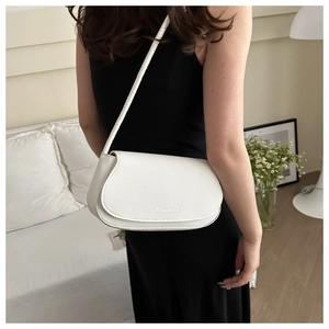 Close-up of a white leather crossbody bag with Fashion engraving and minimalist flap design