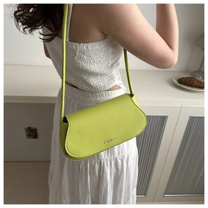 Detailed view of the bright lime green shoulder bag featuring a Fashion print and flap