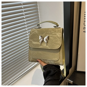 Detailed close-up of light green bow bucket bag with silver butterfly buckle and pleated texture