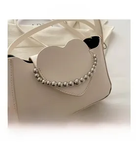 Detail of off-white heart-shaped flap bag with stylish silver metal bead chain accents