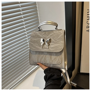 Detail of silver metallic butterfly clasp on a textured faux leather handbag handle