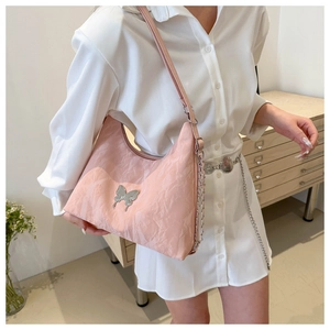 Gros plan d'un sac plissé rose avec boucle papillon argentée et bandoulière en chaîne