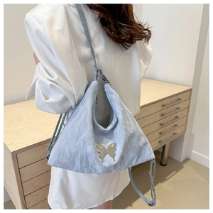 Détail du sac à bandoulière bleu clair plissé avec papillon en métal et chaîne