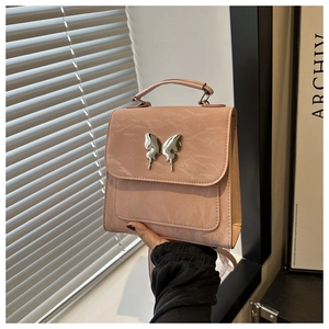 Detailed view of pink crinkled handbag with large silver butterfly metallic hardware