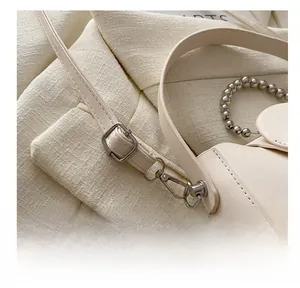 Detailed view of the adjustable thin shoulder strap with silver buckle on beige leather bag