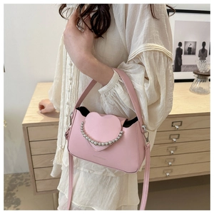 Detailed view of the pink heart-shaped flap and metallic bead chain on the crossbody bag