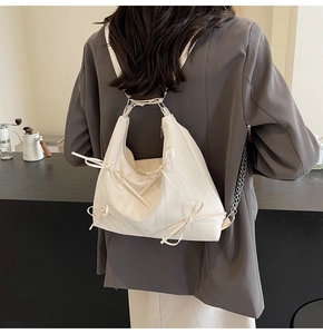 Vue détaillée du sac hobo blanc crème avec nœuds décoratifs et bandoulière en chaîne