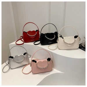 Detail view of colorful beaded crossbody bags with heart-shaped flap and metallic chain