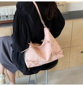 Vue détaillée du sac croissant plissé rose avec nœuds et bandoulière chaîne