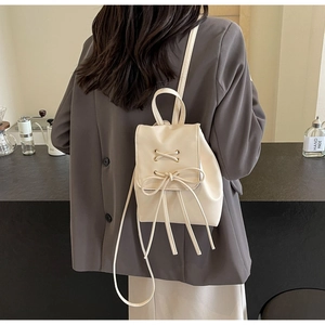 Detail view of cream white PU leather backpack with tassel bow and drawstring accents