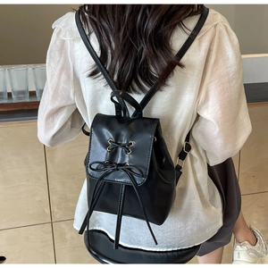 Détail d'un mini sac à dos en cuir PU noir avec nœuds et œillets métalliques dorés