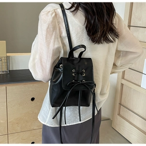 Modern black mini backpack with ribbon bow detail on model in bright room
