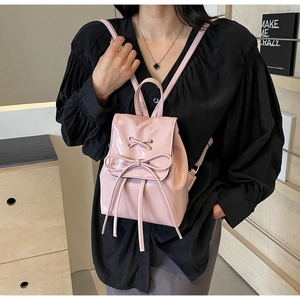 Détail d'un sac à dos rose en similicuir avec nœud élégant et fine bandoulière