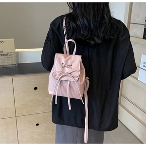 Détail d'un mini sac à dos en similicuir rose avec nœud porté par un mannequin