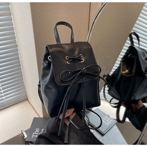 Detail view of small black backpack with lace-up bow design via mirror reflection