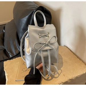 Detail of silver metallic backpack with decorative bow on stone pedestal display