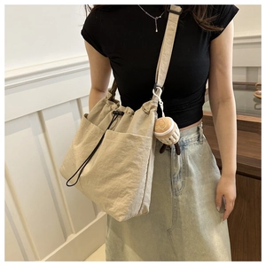 Detail of adjustable shoulder strap and drawstring side pocket on the beige tote bag