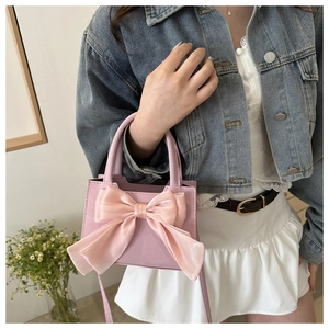 Detail of pink bow-knot handbag with matte leather texture and detachable strap