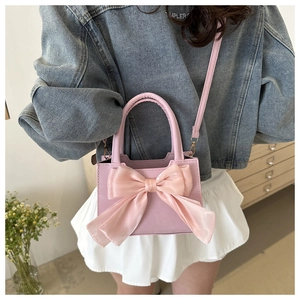 Pink crossbody bag featuring a large organza bow detail shown on a model