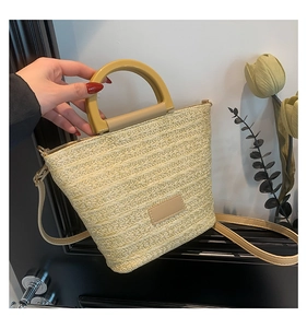 Close-up of woven straw texture with acrylic handles and adjustable leather shoulder strap