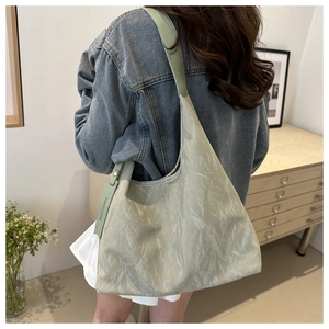 Détail du sac cabas vert clair avec texture plissée et étiquette de mode sur un mannequin