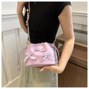 Détail du sac seau lavande à cordon avec nœuds en satin et bandoulière dorée