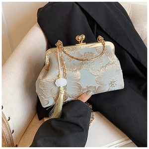 Detail of light blue satin clutch bag with gold flower embroidery and pearl tassels