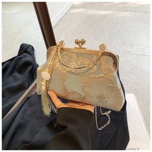 Detailed shot of retro floral embroidery on a vintage kiss lock handbag with gold tassel