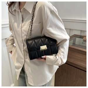 Detail of black quilted leather shoulder bag with gold square buckle and chain strap