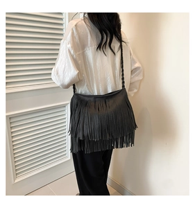 Detail view of black fringe hobo bag featuring woven straps on female model back