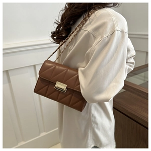 Close-up of brown quilted leather crossbody bag with gold chain strap and metal clasp