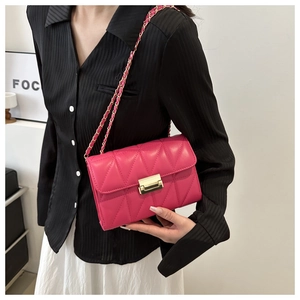 Close-up of fuchsia quilted crossbody bag with gold metal buckle and chain strap