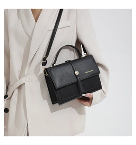 Gros plan d'un sac à main noir en cuir avec fermoir doré et lettrage élégant