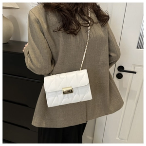 Detailed back view of model wearing white quilted crossbody bag with gold chain strap