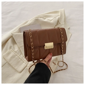 Close-up of warm brown quilted leather flap bag with gold chain strap and square buckle