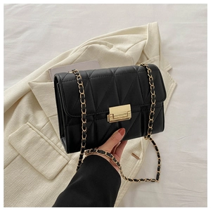 Detailed view of black quilted flap bag with golden metal clasp and chain strap