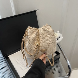 Sac seau tissé beige avec fermeture à cordon et bandoulière en chaîne dorée