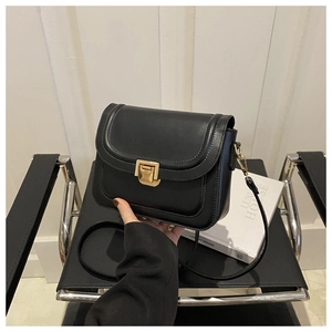 Détail du sac bandoulière noir avec fermoir doré et surpiqûres blanches élégantes