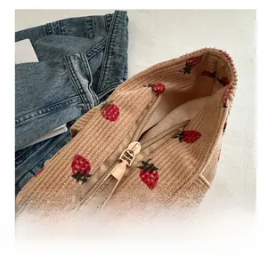 Close-up of smooth metal zipper and red strawberry pattern on corduroy tote bag