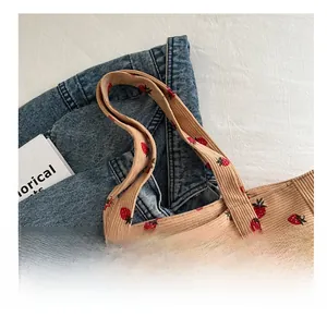 Detail of corduroy tote bag featuring red strawberry patterns and sturdy double handles