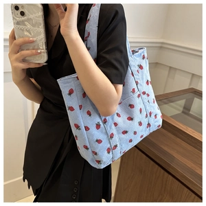 Detail of light blue corduroy tote bag with strawberry print and side pocket