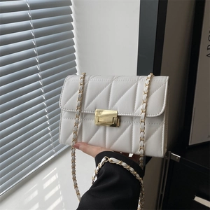 White quilted crossbody bag with gold chain strap and square metal clasp in natural light