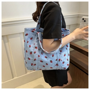 Detail of light blue corduroy tote bag with strawberry print and wide shoulder straps